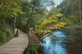 Wooden path along the river bank surrounded by trees on an autumn sunny day Royalty Free Stock Photo