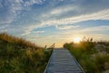 Wooden path at Baltic sea over sand dunes with ocean view, sunset summer evening