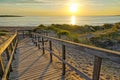 Wooden path at Baltic sea over sand dunes with ocean view, sunset summer evening