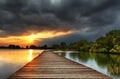 Wooden path bridge over lake at stormy dramatic sunset Royalty Free Stock Photo