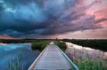 Wooden path bridge over river at stormy sunset