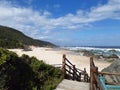 Wooden path leading to secluded beach with rocks and coastal bush Royalty Free Stock Photo