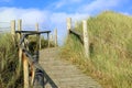 Wooden path through sand dunes with blue cloudy sky Royalty Free Stock Photo