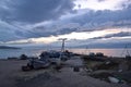 Wooden path to pier with old ships and boats in evening at sunset with blue clouds on lake baikal, mountains on horizon Royalty Free Stock Photo