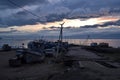 wooden path to pier with old ships and boats in the evening at sunset with dark blue clouds on lake baikal, mountains Royalty Free Stock Photo