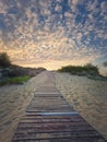 Wooden pathway through the sand leading to the beach and a beautiful morning sky with fluffy clouds Royalty Free Stock Photo