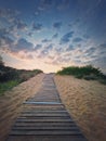 Wooden pathway through the sand leading to the beach. Beautiful morning sky with fluffy clouds Royalty Free Stock Photo