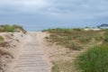 Wooden pathway to the beach and cloudy sky in the background Royalty Free Stock Photo