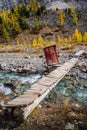 Wooden pedestrian bridge over the Aktru River and a booth with scientific equipment