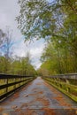 A wooden pedestrian bridge runs over a creek surrounded by trees on the Neuse River greenway in Raleigh, North Carolina, USA Royalty Free Stock Photo