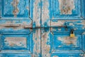 Wooden peeled blue door, closed, locked, aged for background. Rusty latch and padlock. Close up view. Royalty Free Stock Photo