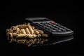 Wooden pellets and calculator on black background. The concept of paying for heating Royalty Free Stock Photo