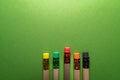 Wooden pencils with colorful erasers on green background