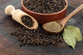 Wooden pepper mill, black peppercorns, ground black pepper and laurel leaves on old wooden table Royalty Free Stock Photo