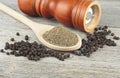 Wooden pepper mill, black peppercorns and ground black pepper on old wooden table Royalty Free Stock Photo