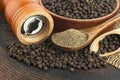 Wooden pepper mill, black peppercorns and ground black pepper on old wooden table Royalty Free Stock Photo