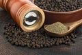 Wooden pepper mill, black peppercorns and ground black pepper on old wooden table Royalty Free Stock Photo