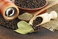 Wooden pepper mill, laurel leaves, black peppercorns and ground black pepper on wooden table Royalty Free Stock Photo