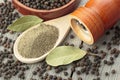 Wooden pepper mill, laurel leaves, black peppercorns and ground black pepper on old wooden table Royalty Free Stock Photo