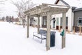 Wooden pergola over bench and garbage can against buildings and white sky