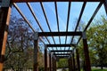 Wooden pergola or trellises for climbing plants over the promenade with benches. the wooden mass frame protrudes on the cables whi Royalty Free Stock Photo