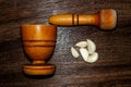 wooden pestle and mortar with garlic cloves on a textured Royalty Free Stock Photo