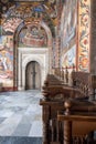 Colorful fresco lined corridor with wooden pews, Rila Monastery, Bulgaria Royalty Free Stock Photo
