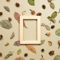 Wooden photo frame with autumn dry leaves on khaki brown background