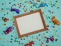 Wooden photo frame, multicolored streamer and small candies on a light blue background.