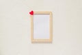 Wooden photo frame with red heart on white wall baxkground. Minimal flat lay with copy space Royalty Free Stock Photo