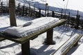 A wooden picnic table and benches covered in a thick layer of snow against a snow-covered winter country landscape. Royalty Free Stock Photo