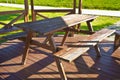 Wooden picnic table in a wooden gazebo on a green meadow in a public park