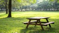 Wooden picnic table in sunny park surrounded by lush greenery and trees Royalty Free Stock Photo