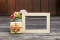 Wooden picture frame with gift box and paper flower on wooden floor Royalty Free Stock Photo