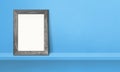 Wooden picture frame leaning on a blue shelf. 3d illustration. Horizontal banner Royalty Free Stock Photo