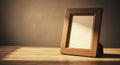 Wooden picture frame on a wooden surface, set against a neutral, subtly lit backdrop. Royalty Free Stock Photo