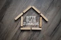 Wooden pieces with the german words for Stay Home - Bitte bleib zuhause on wooden background Royalty Free Stock Photo