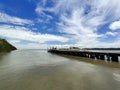 a wooden pier against a backdrop of white clouds and a clear blue sky and a boat leaning against it Royalty Free Stock Photo