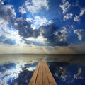 Wooden pier on big lake and sky reflection Royalty Free Stock Photo