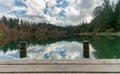 Wooden pier and boardwalk with dock pylons on the edge of an idyllic mountain lake surrounded by fall color forest Royalty Free Stock Photo