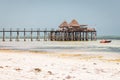 Wooden pier with boat and beach hut. Low tide of Indian Ocean. Idyllic exotic resort. Pier in perspective with bungalow. Royalty Free Stock Photo