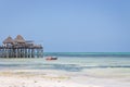 Wooden pier with boat and beach hut. Low tide of Indian Ocean. Idyllic exotic resort. Pier in perspective with bungalow. Royalty Free Stock Photo