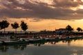 Wooden pier with a boat in the town of Podersdorf on Lake Neusiedl in Austria. In the background is a dramatic sunset sky