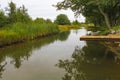 A wooden pier bridge over a river that goes into the distance along the reeds. A scene of calm pacified village life