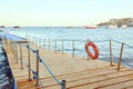 Wooden pier of Dive Station. Life belt. Yachts on the horizon.