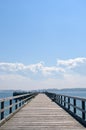 Wooden pier extending into ocean, hazy blue sky