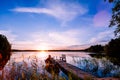 Wooden pier with fishing boat at sunset on a lake in Finland Royalty Free Stock Photo