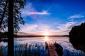 Wooden pier with fishing boat at sunset on a lake in Finland Royalty Free Stock Photo