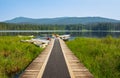 Wooden pier on the forest lake. Summer landscape at the Whonnock Lake. Shore of a lake with a wooden pier and tied boats Royalty Free Stock Photo