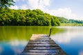 Wooden pier or jetty and a boat on lake sunset and sky reflection water. Royalty Free Stock Photo